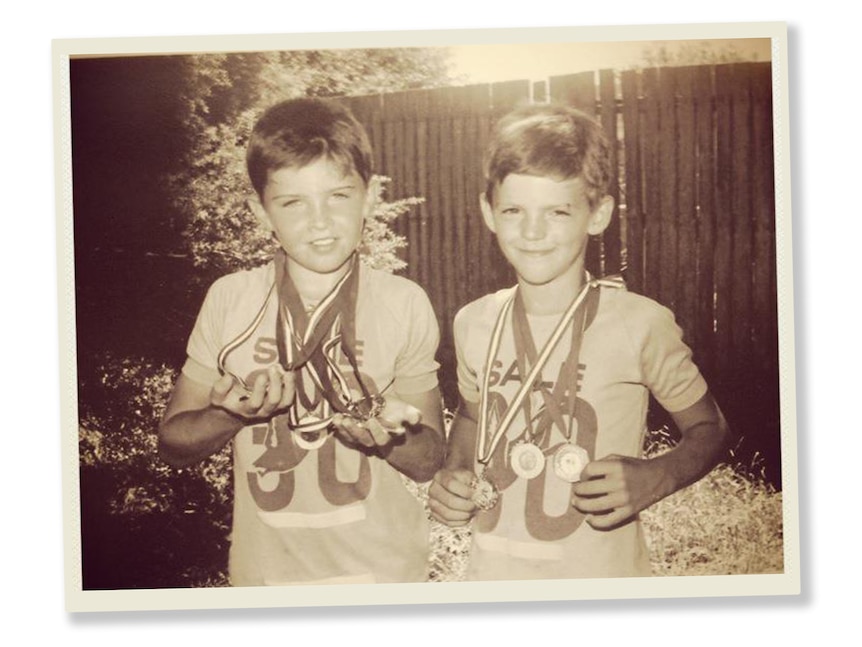 A sepia photo of two boys wearing medals in a backyard.
