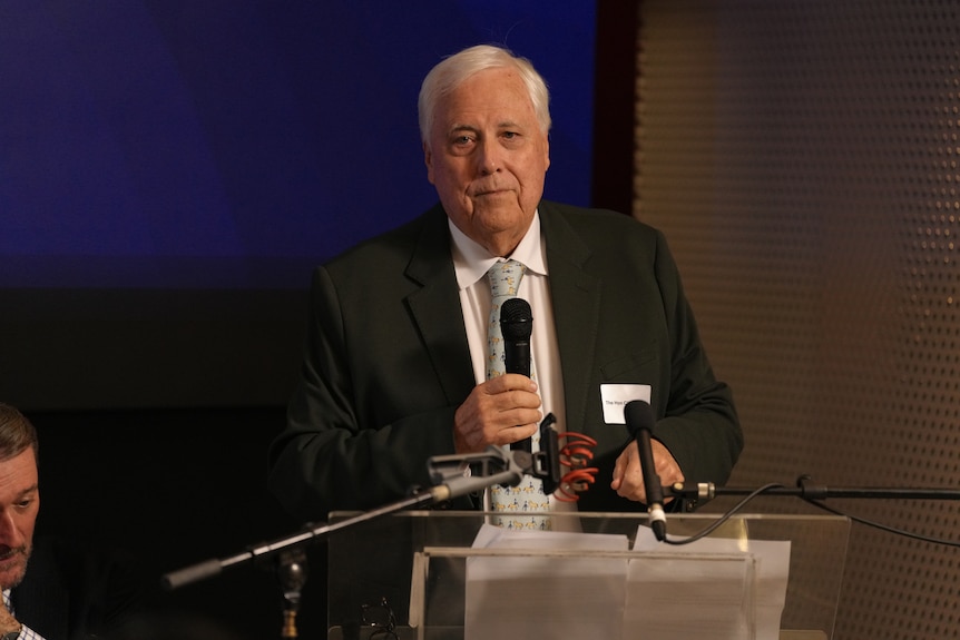 A man in a suit standing at a lectern speaking.