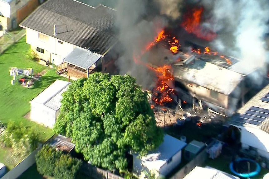 Aerial photo showing flames engulfing a house and surrounding homes.
