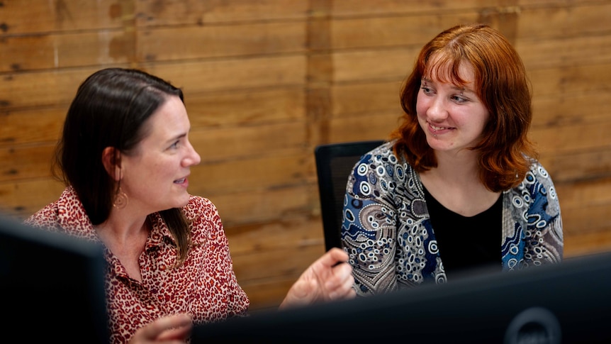 Two women looking at a computer screen and chatting