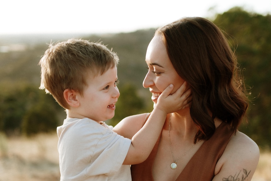 Mother and son embrace outside in nature 
