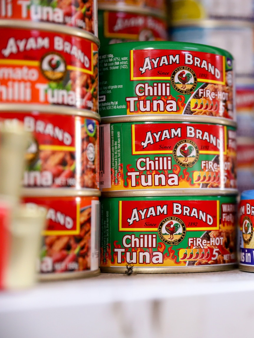 Rows of brightly coloured cans of chilli tuna for sale on a supermarket shelf