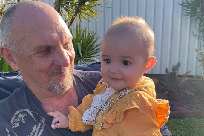 Grandad with little girl in yellow dress, smiling at eachother