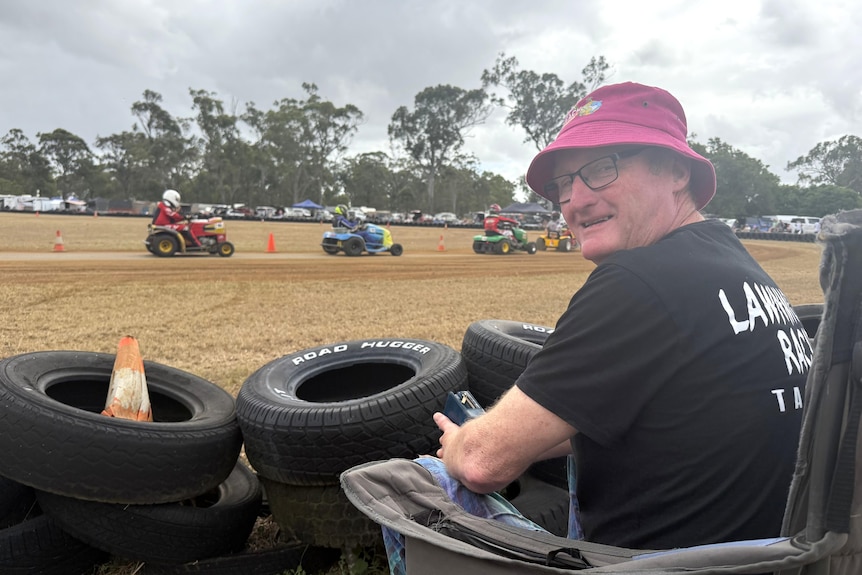 A man looking on from the edge of a race track.