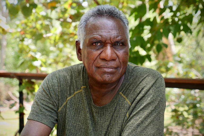 An Aboriginal man sits outside with a serious expression