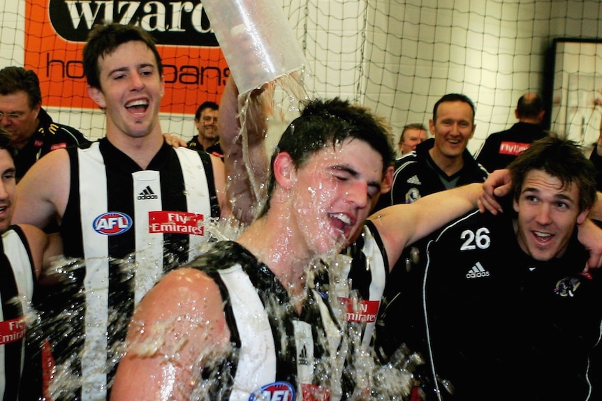 Scott Pendlebury is showered with water during the team song