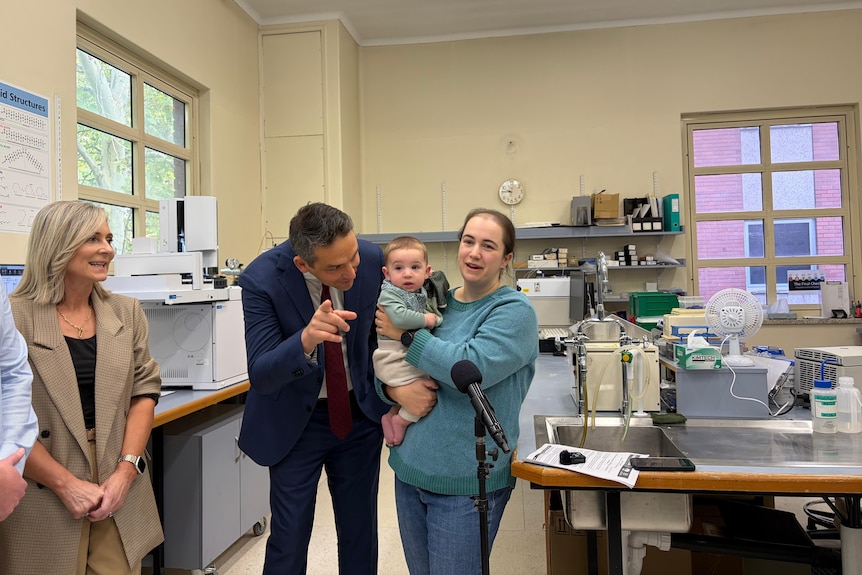 People standing, with a baby, in front of a microphone in a lab