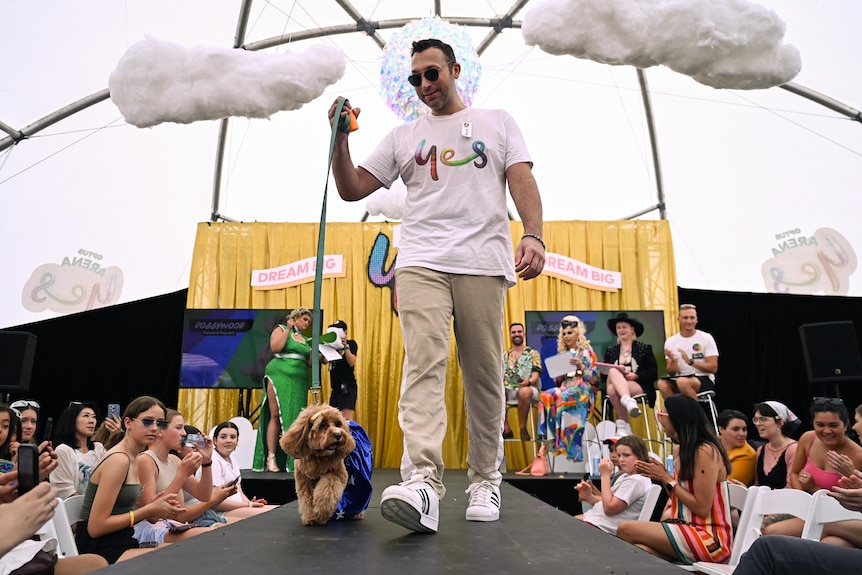 Ian Thorpe walks a dog down a catwlk wearing a t-shirt that says 'yes' in rainbow letters
