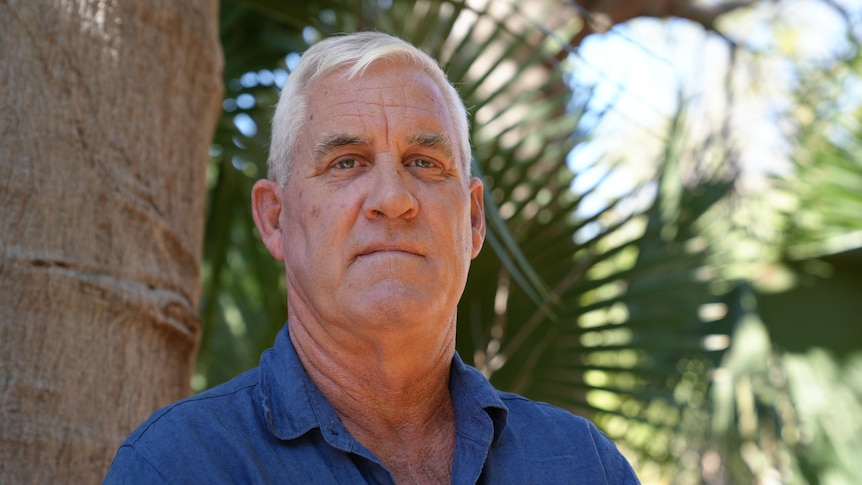 White man with with hair and blue eyes posing near a boab tree 