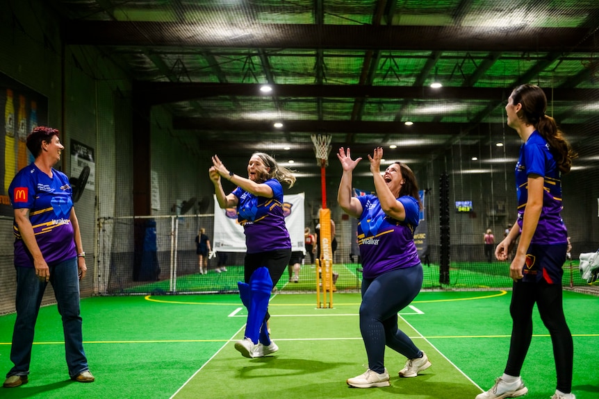 Women mucking around in indoor cricket stadium