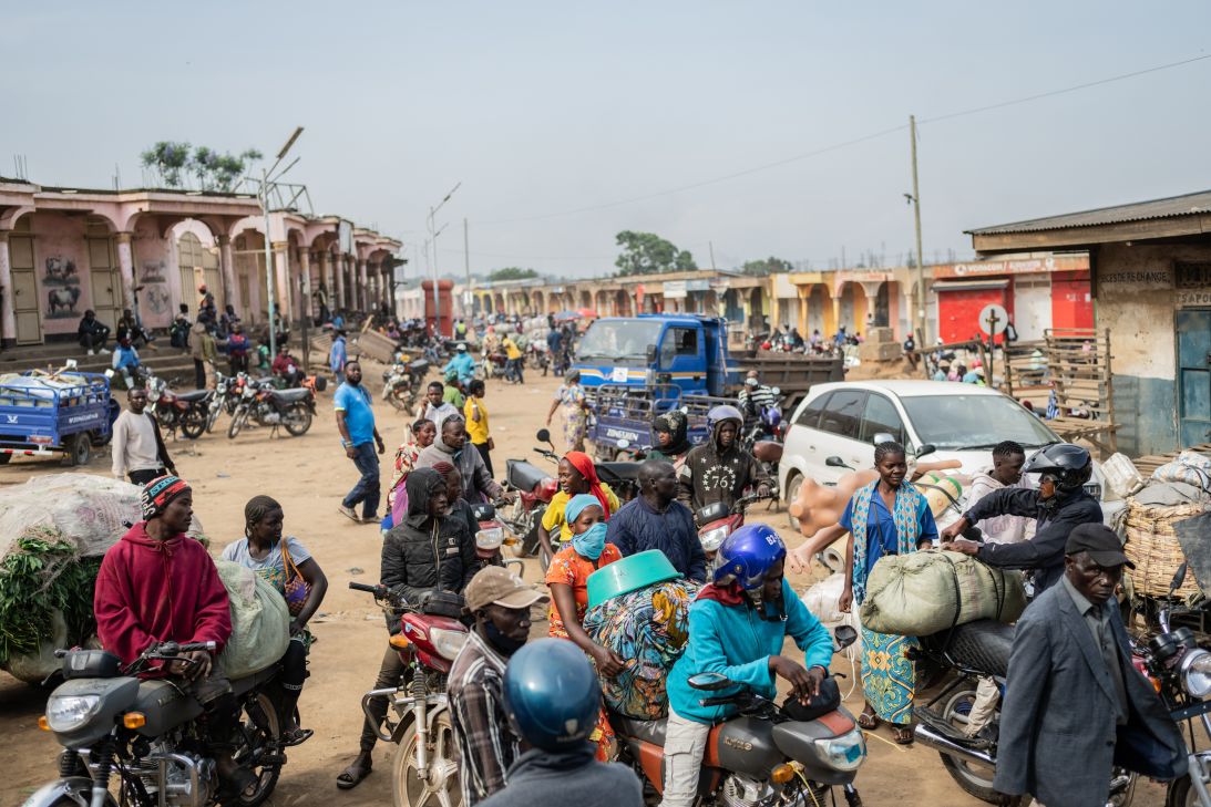 Motorcycle taxi riders and their passengers wait at the entrance to the central market while sanitation workers disinfect the area, as Ituri province continues to combat an Ebola outbreak in Bunia, DRC, Saturday, May 23, 2026. (AP Photo/Moses Sawasawa)
