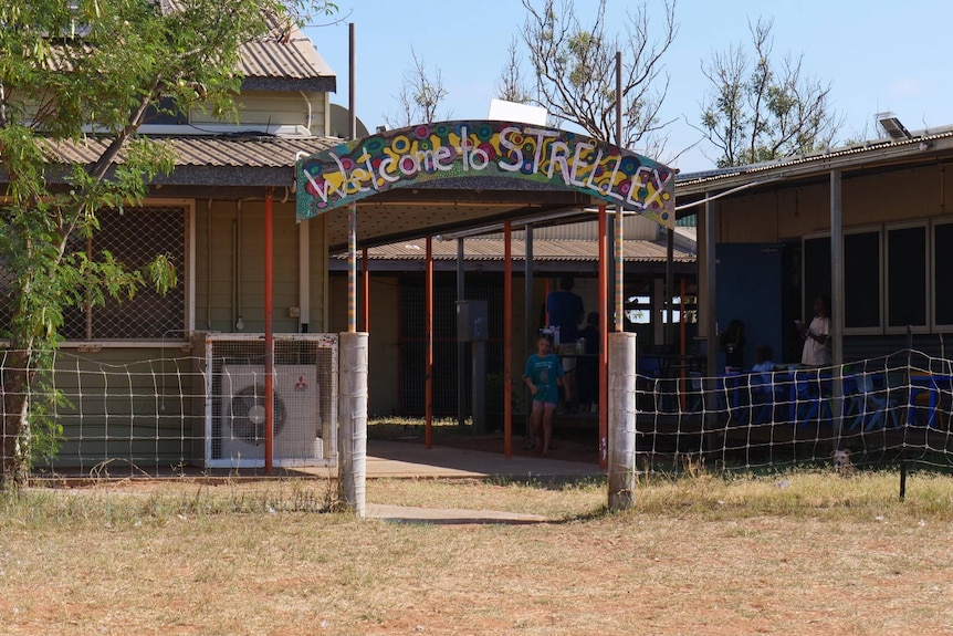 The entrance to a school courtyard, with a big colourful sign reading "Welcome to Strelley".