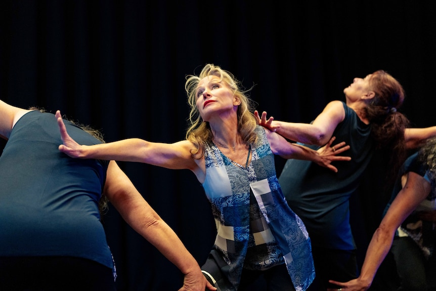 Mature-aged women doing dance practise in a studio with blue light