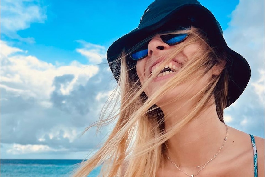 A woman with blonde hair smiling wearing a hat