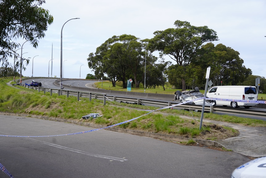Police tape around two crashed cars on a road.