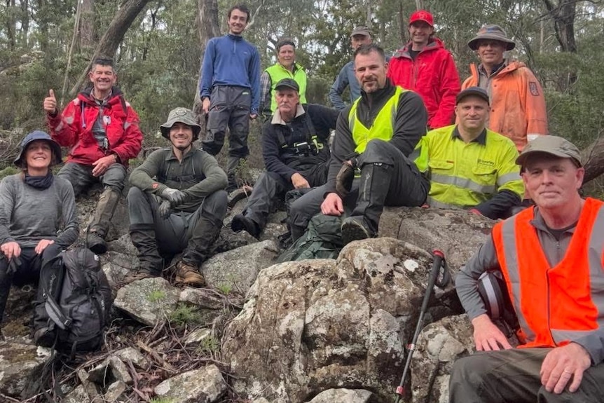 A group of people sit on rocks in the bush.