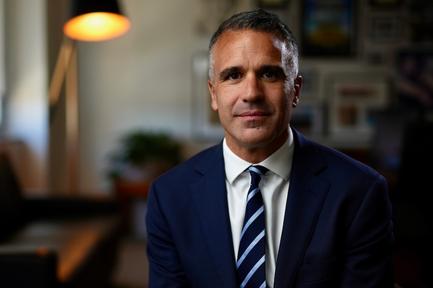 Peter Malinauskas wearing a navy suit sitting in an office.