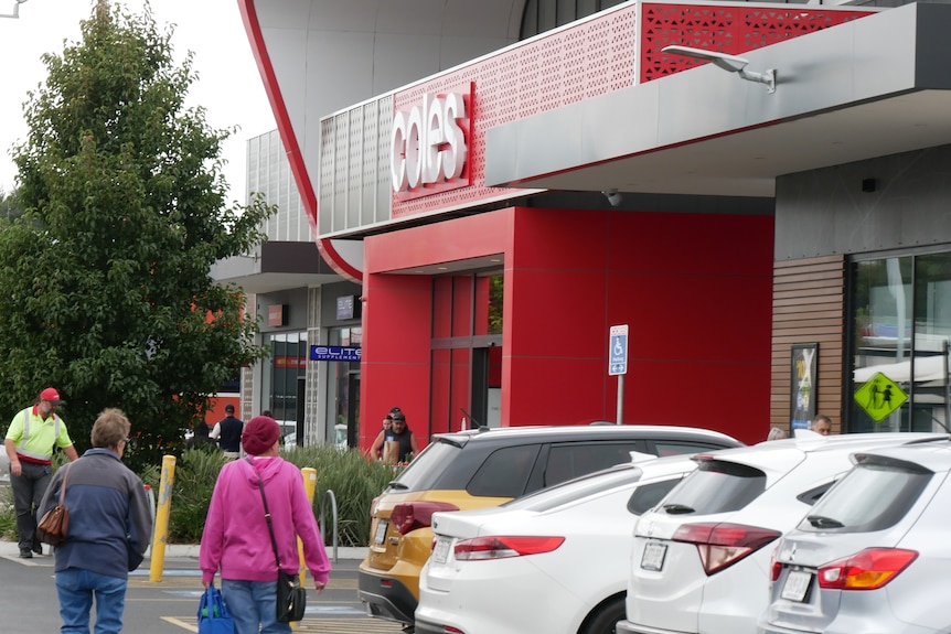 The entrance to a supermarket with cars parked outside.