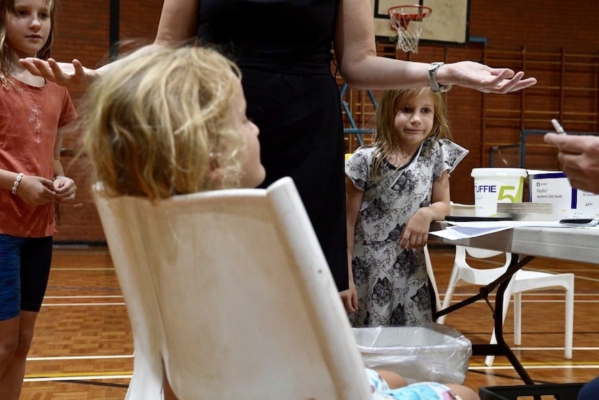 children being vaccinated in a basketball court