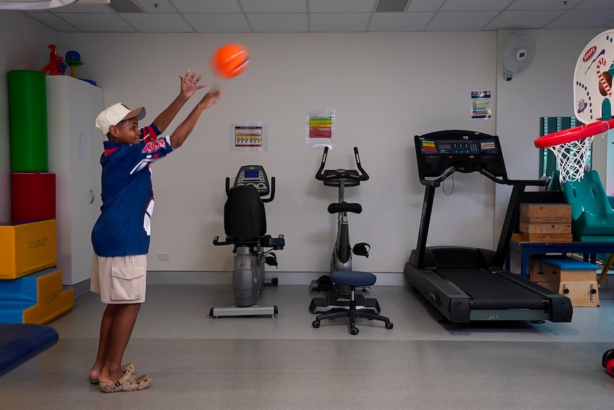 Sam shoots a basketball at an indoor basketball net
