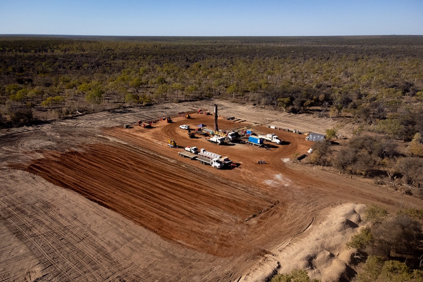 Aerial shot of cleared ground in what is otherwise endless scrub, with a gas drilling gas in the middle
