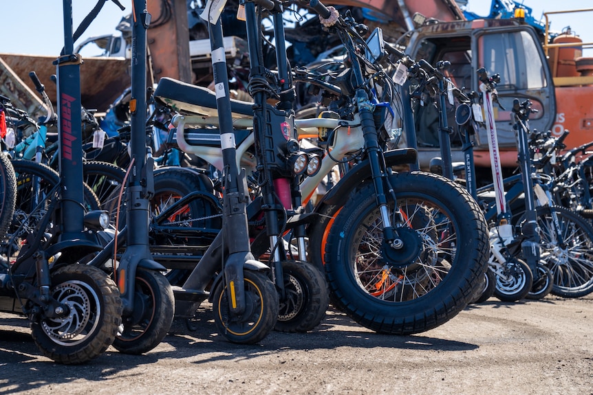 A group of e-rideables, bikes and scooters, sitting in a line.