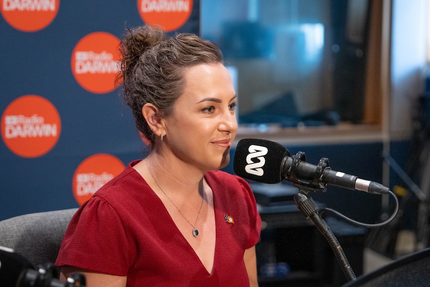 NT Chief Minister Lia Finocchiaro sitting in front of a radio microphone mounted on a table, inside an ABC radio studio.