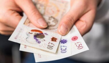 Close-up of a woman holding modern polymer ten, twenty and fifty pound notes.