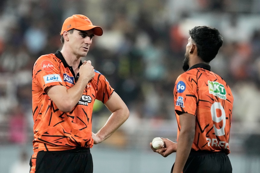 Pat Cummins speaks with Praful Hinge during the IPL