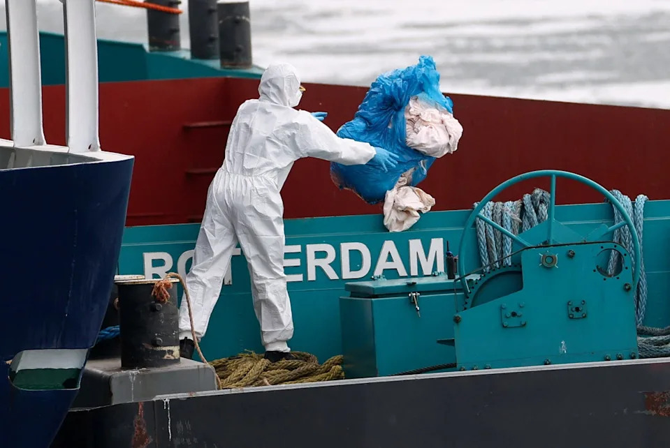 A person wearing protective equipment throws a bag of waste next to the hantavirus-stricken cruise ship MV Hondius at the Port of Rotterdam in the Netherlands last Monday. The ship is being disinfected (Reuters)