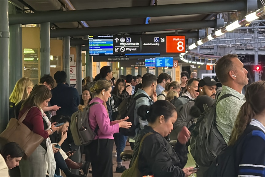 A group of people gathered on a train station platform.