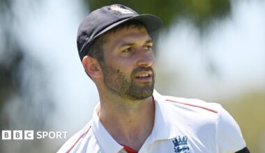 Mark Wood, wearing a blue England cap, looks to the side