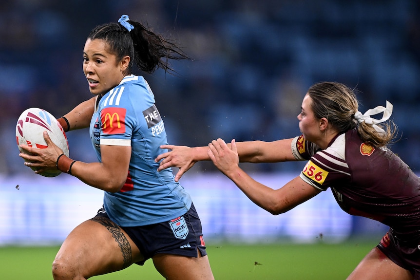 A woman runs the ball during a rugby league match