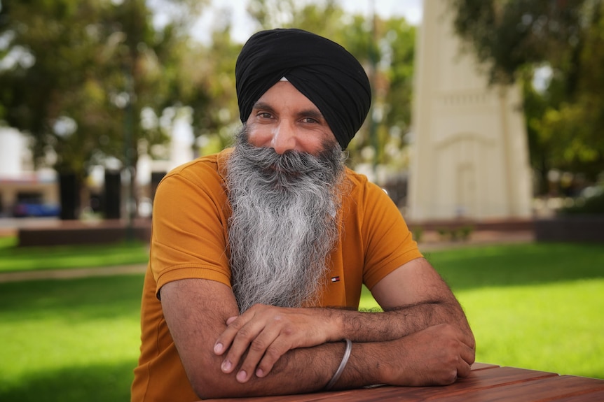 A Sikh man leans on a park table.
