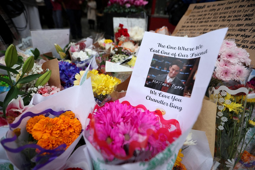 Flowers and posters placed in a makeshift memorial for Matthew Perry in NYC