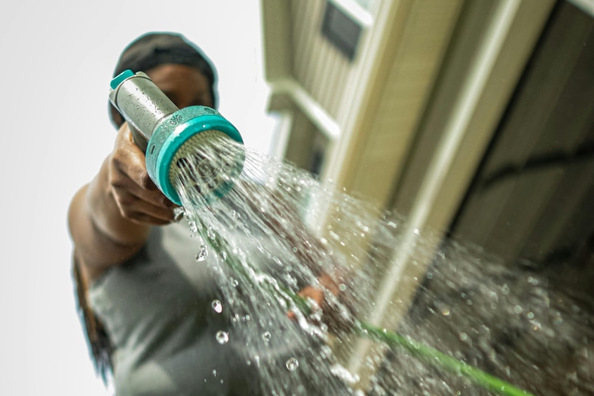 Girl holds hose spraying water.