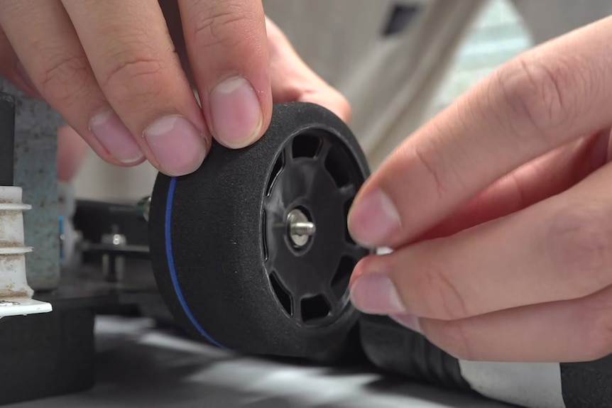 A close up shot of a tyre being affixed to a car's frame