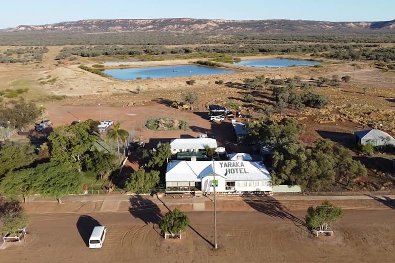 Yaraka Hotel pictured from a drone sitting amongst red dirt and hill in background.