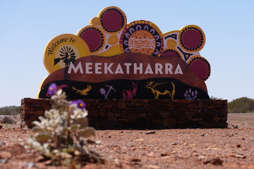 A large stone sign which says "Meekatharra" in front of red dirt.