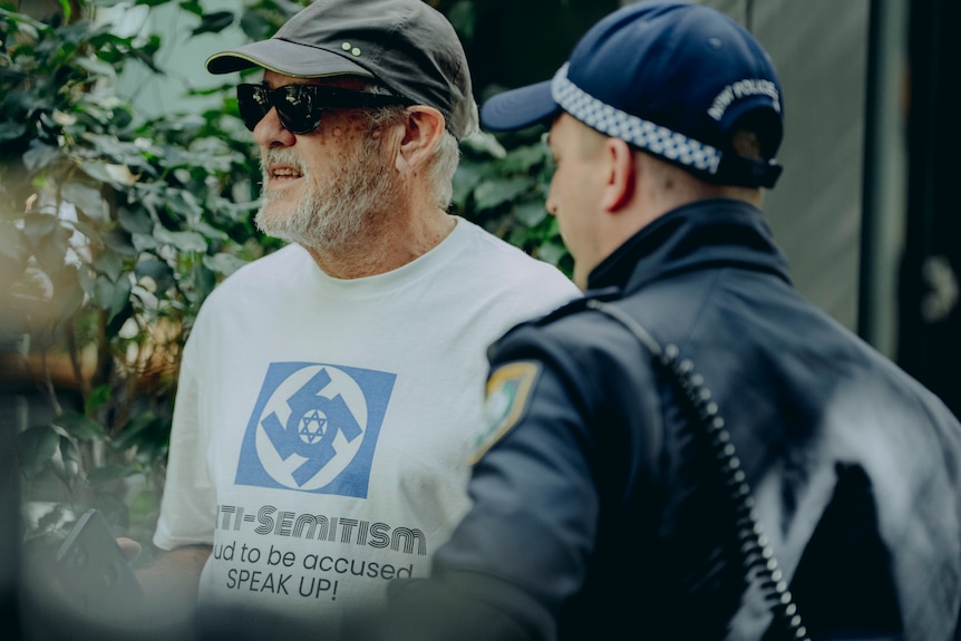 Man in cap with white shirt with blkue swastika and