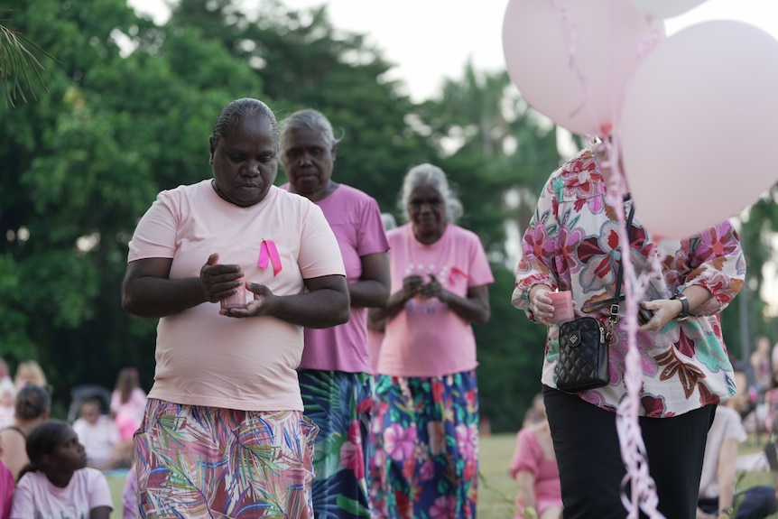 Indigenous women at a vigil, wearing pink and with balloons.