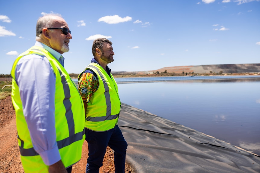 Two executives wearing high-vis vests on a tour of a wastewater treatment plant.