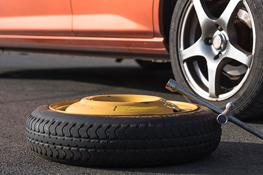 thin tyre horizontal on the road next to the front driver's side wheel of a motor vehicle