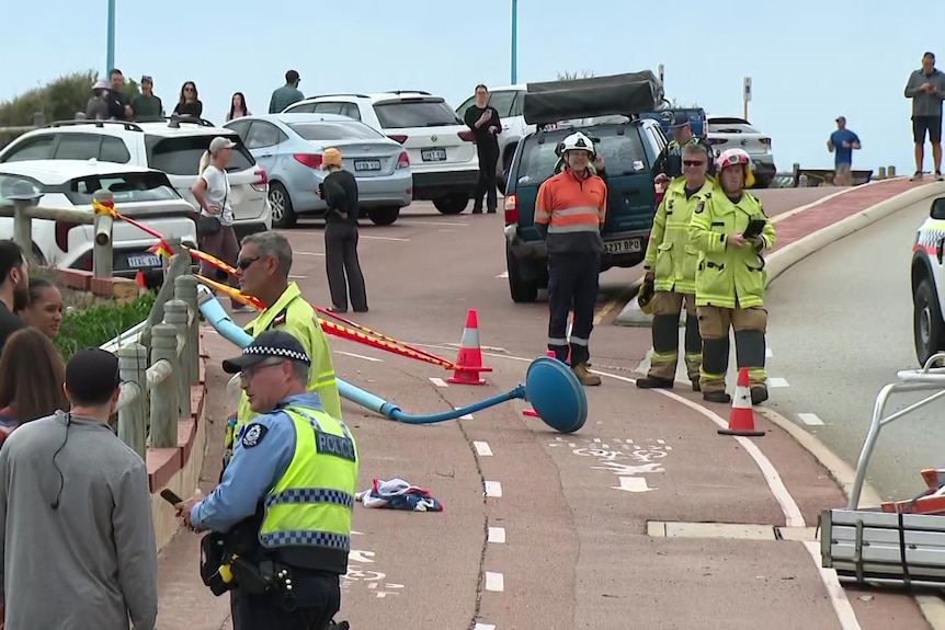 A fallen light pole lies across a pedestrian path