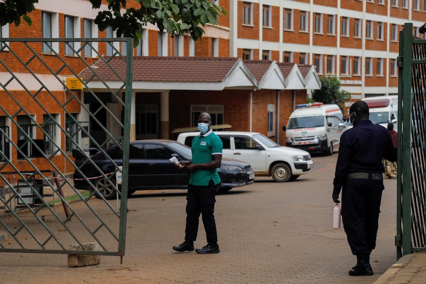 Workers stand guard at the gate of the Kibuli Muslim Hospital where a Congolese man died of Ebola in Kampala, Uganda.