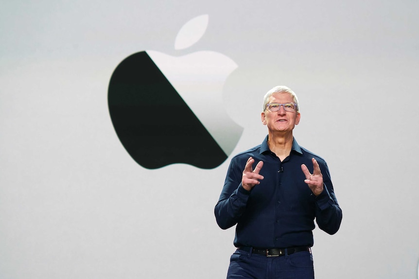 Tim Cook stands in front of a screen with an Apple logo.