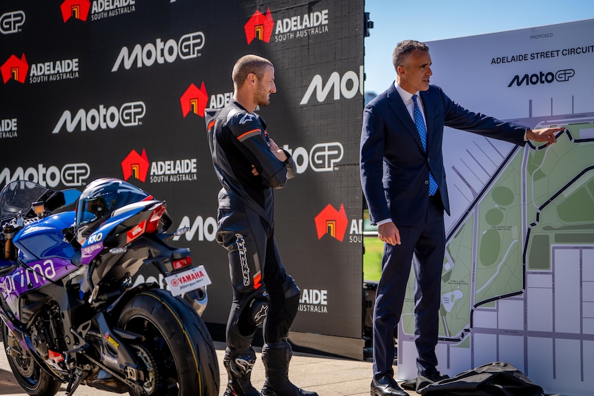 Peter Malinauskas points to a map of the MotoGP street circuit while rider Jack Miller looks on