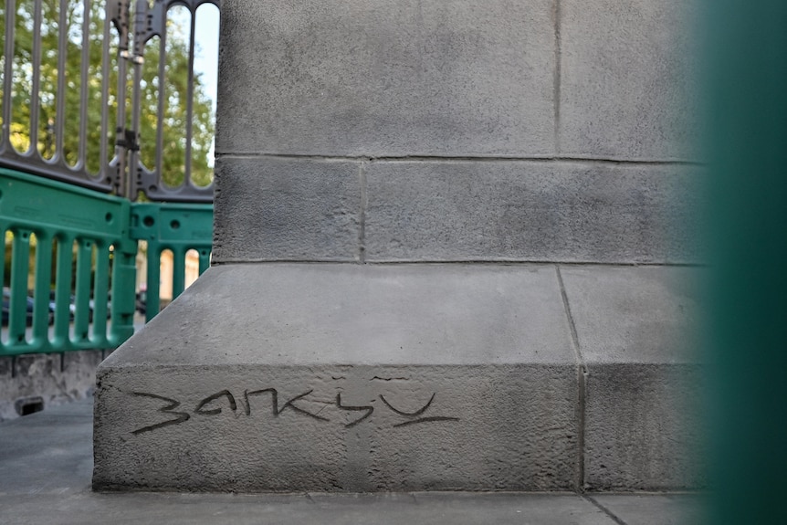 A concrete statue base with the word "Banksy" etched into it. 