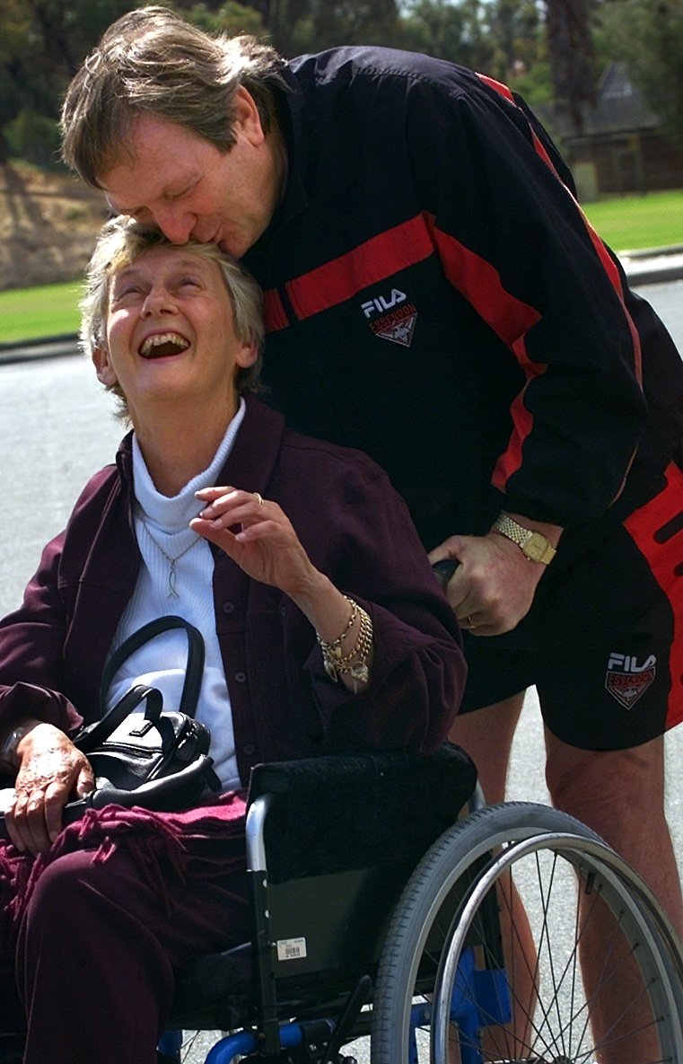 Essendon football coach Kevin Sheedy plants a kiss on the forehead of his childhood idol Betty Cuthbert Picture: Tony Ashby