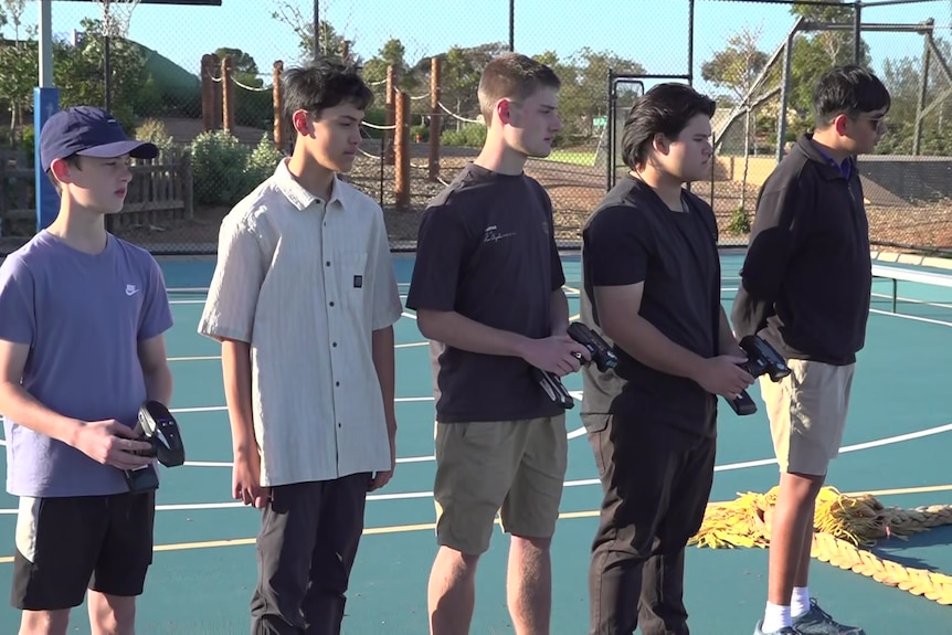 A group of five teens holding the controllers for RC cars